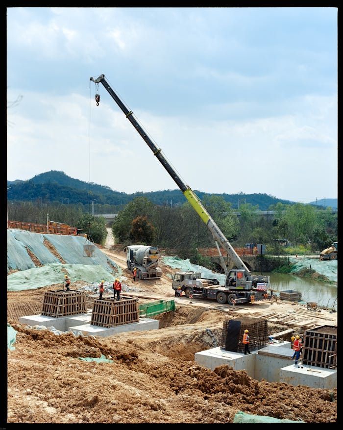 services-01 Active construction site featuring crane operation and workers amid a natural landscape.