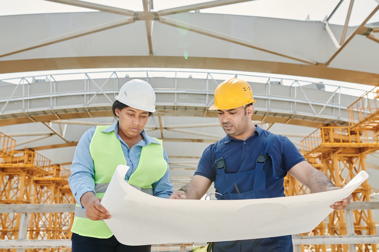 about-04 Male and female engineers discussing blueprints at a construction site, promoting teamwork and planning.